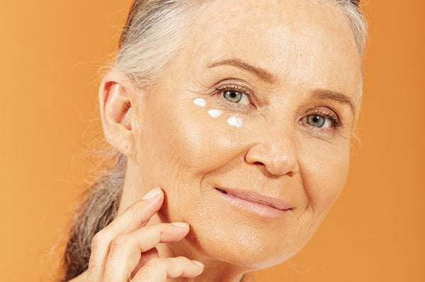 Woman over 50 applying eye cream, skincare for menopause