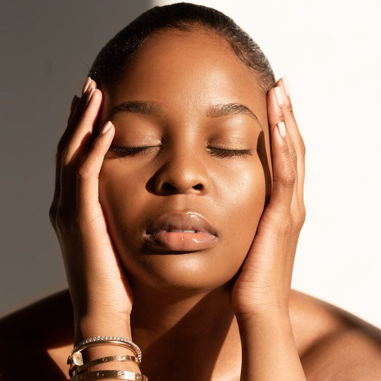 Woman closed eyes radiant healthy skin holding face in hands