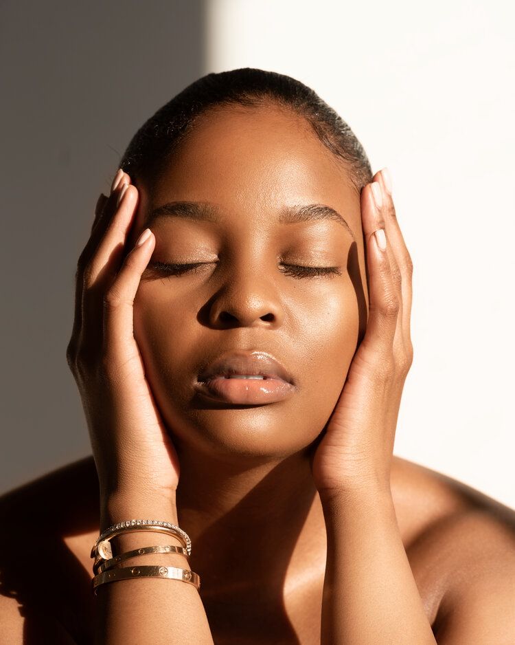 Woman closed eyes radiant healthy skin holding face in hands