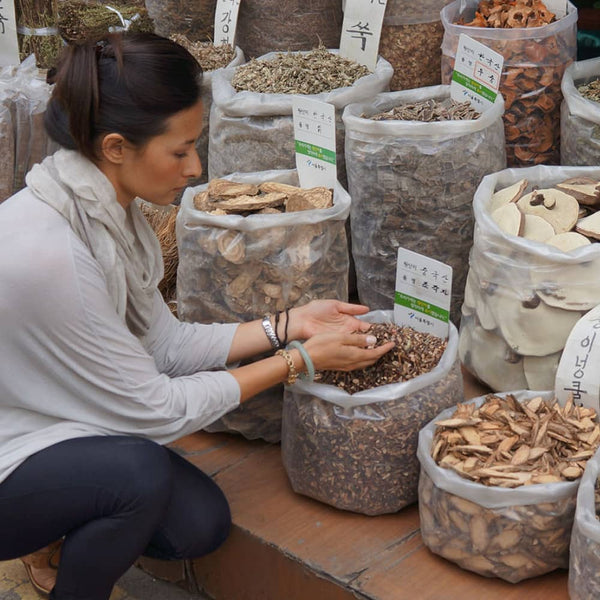 Dr Jenelle Kim kneeling down to examine a bag of herbs