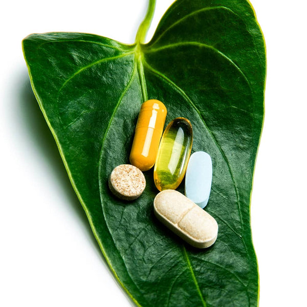 Vitamin supplement capsules on a green leaf