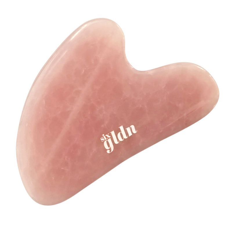 rose quartz crystal gua sha with a white logo six gldn engraved in it against a white background
